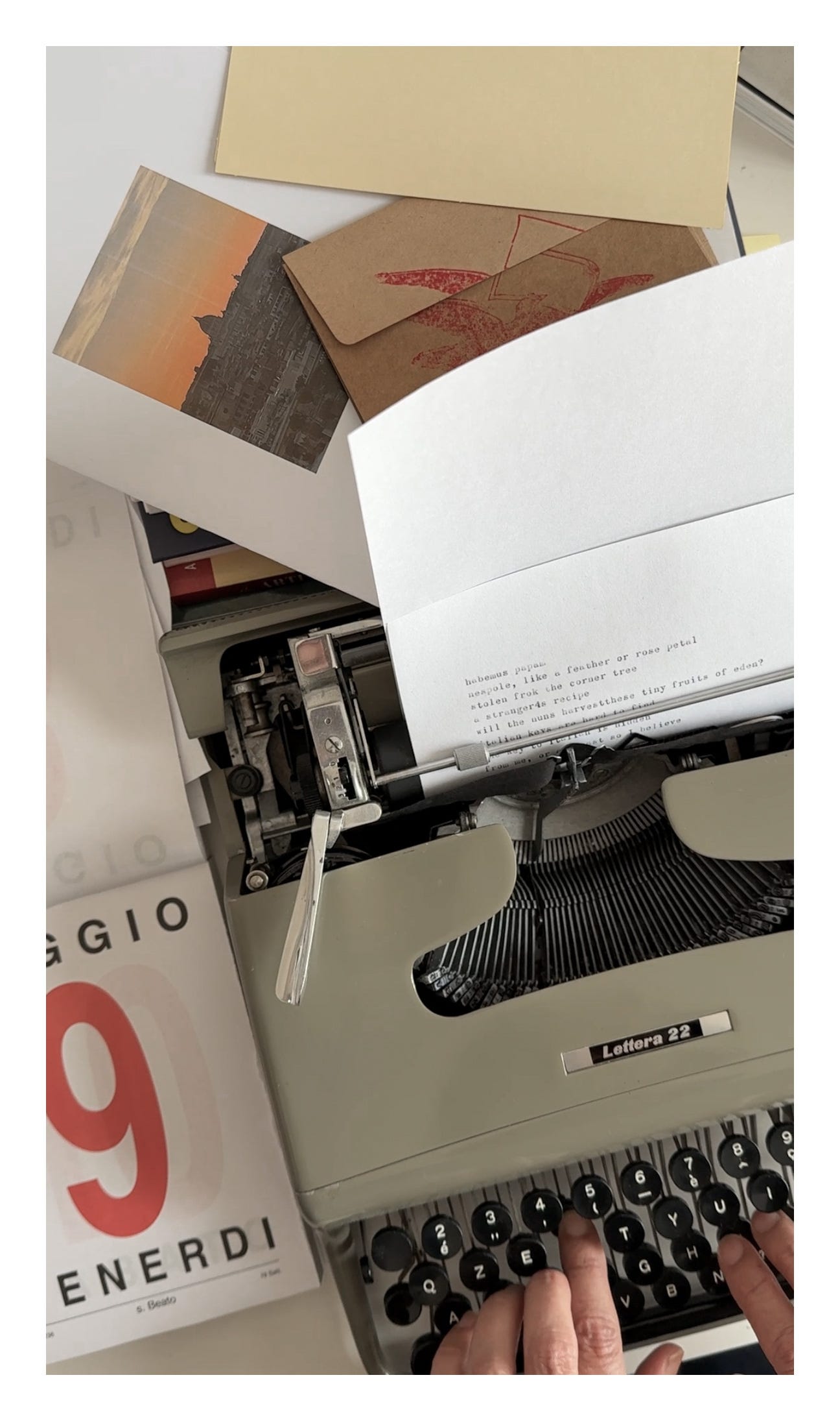 A pair of hands typing on an Olivetti Lettera 22 typewriter, surrounded by postcards, envelopes, and a calendar page marked May 9th – capturing a nostalgic writing moment in Rome.