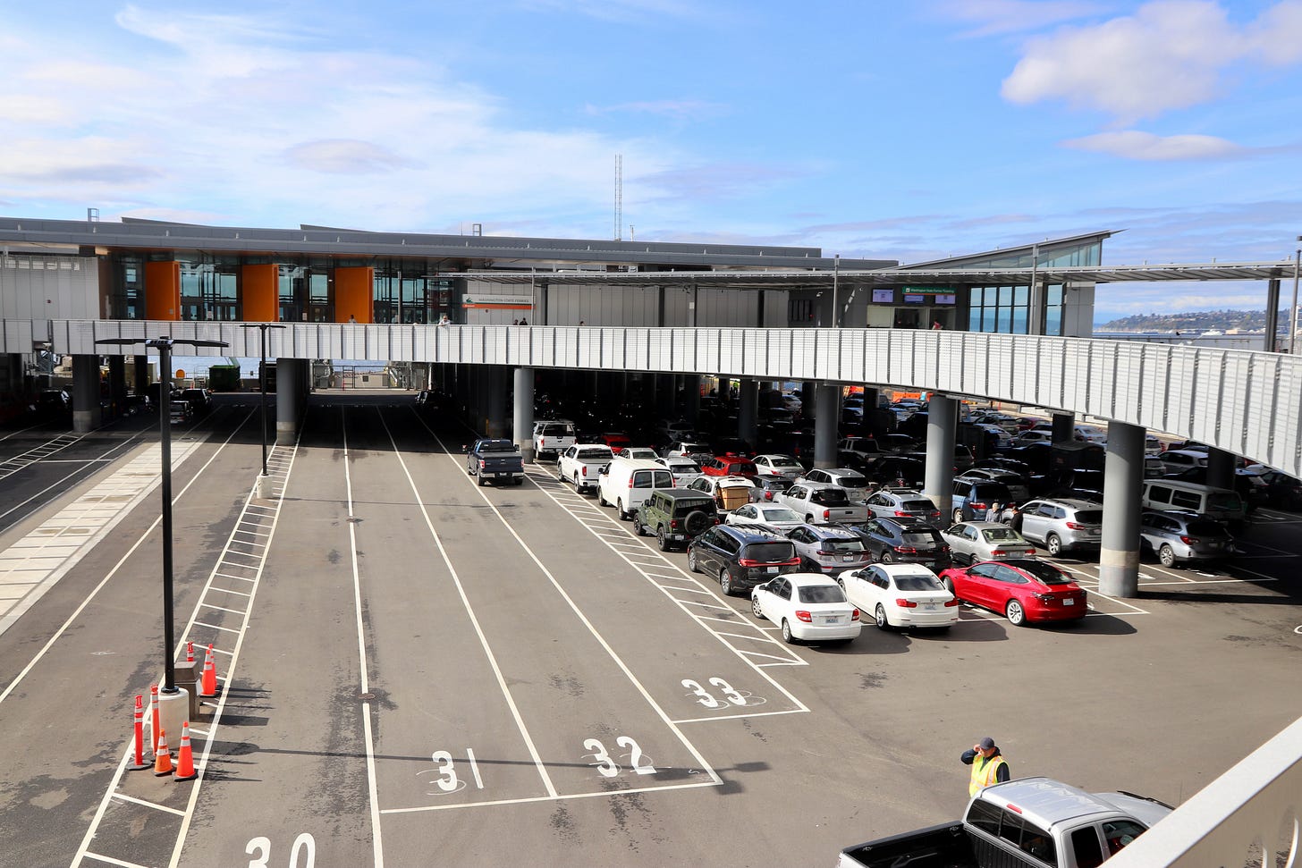A curving upper-level walkway frames the waiting cars parked below. 