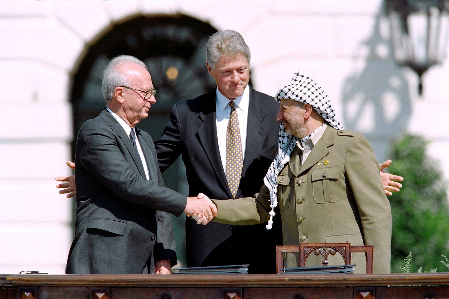 Israeli Prime Minister Yitzhak Rabin and Palestine Liberation Organization Chairman Yasser Arafat shaking hands alongside U.S. President Bill Clinton after signing the Oslo Accords on September 13, 1993 in Washington, D.C.  J. David Ake/AFP via Getty Images