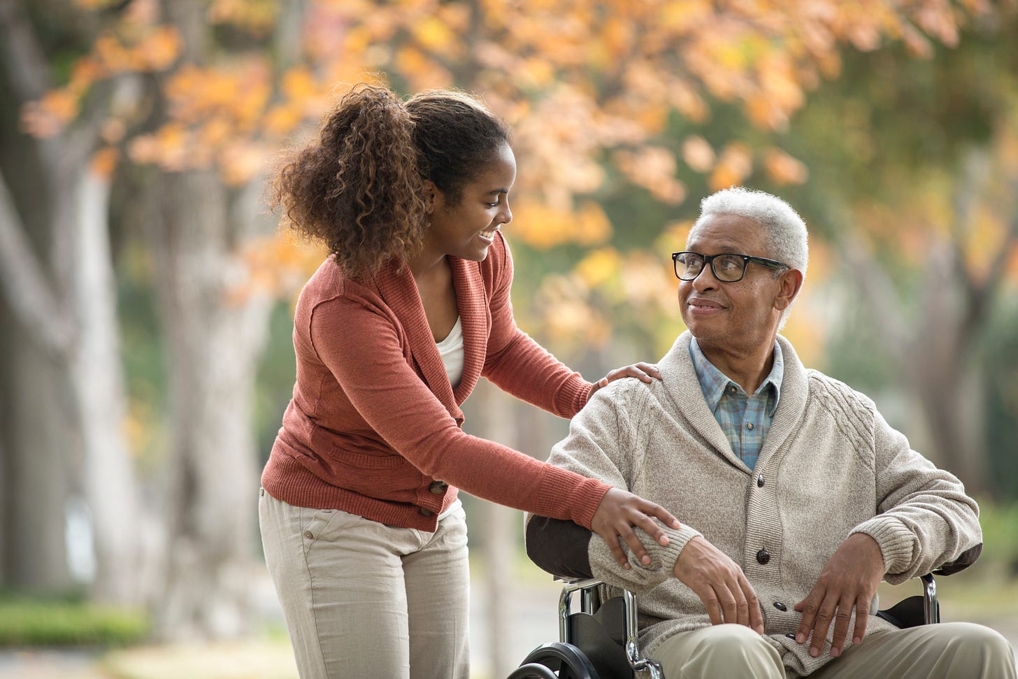 African American woman with elderly father in wheelchair African American woman with elderly father in wheelchair