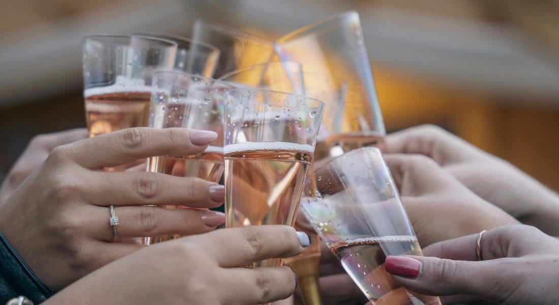A cluster of prosecco glasses being clinked together by manicured hands A cluster of prosecco glasses being clinked together by manicured hands