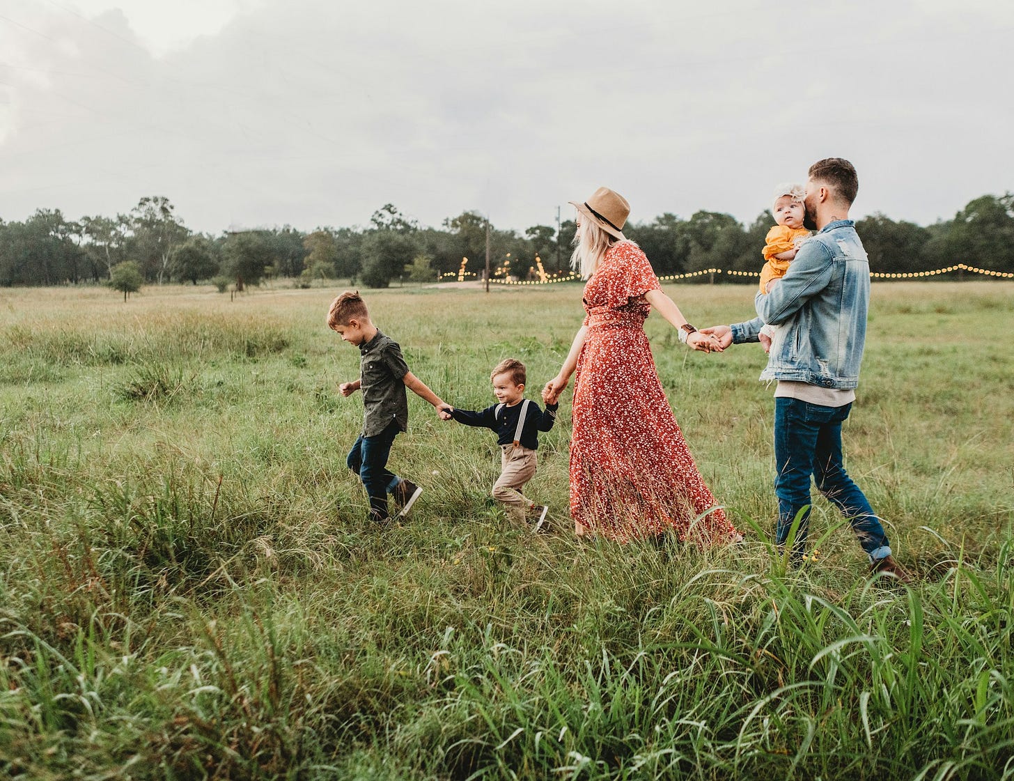 Family enjoying a budget-friendly outdoor walk in a grassy field. Photo by Jessica Rockowitz on Unsplash