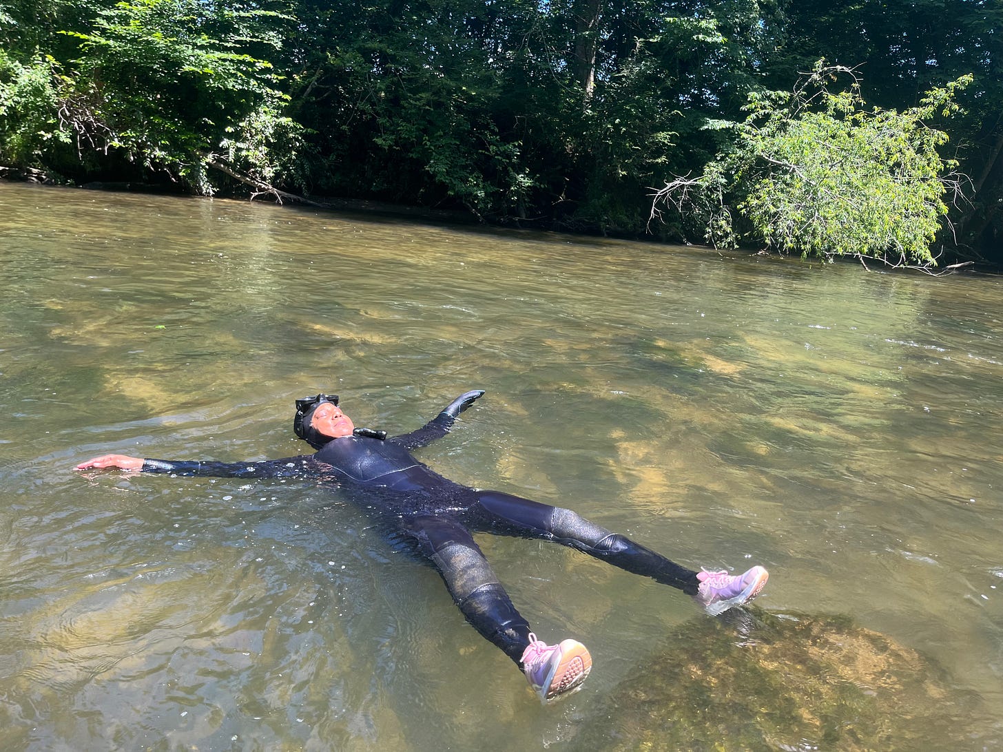 Woman in a wetsuit floating on her back in a river