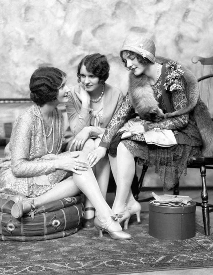 This may contain: three women sitting on a chair talking to each other