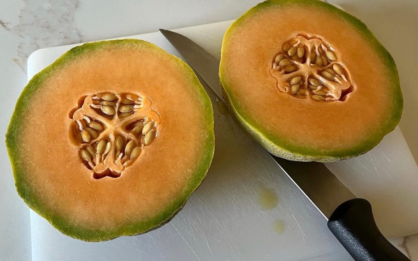 two halves of cantaloupe with knife on counter