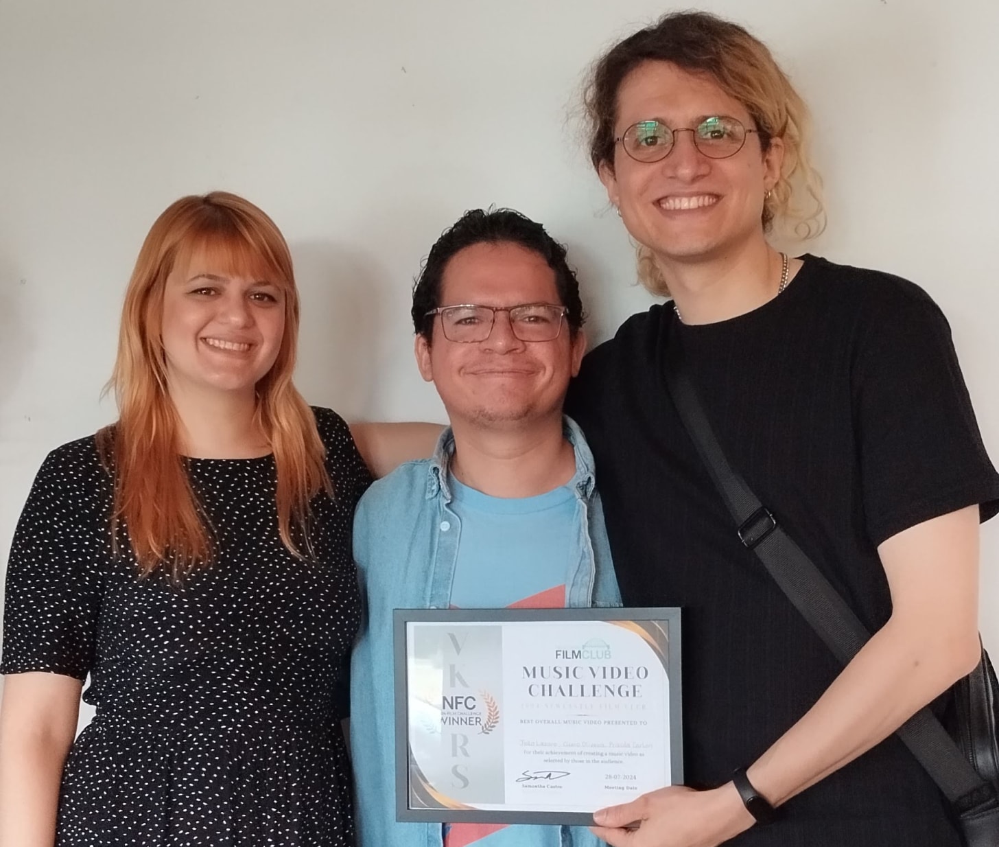 Three people holding an award plaque.