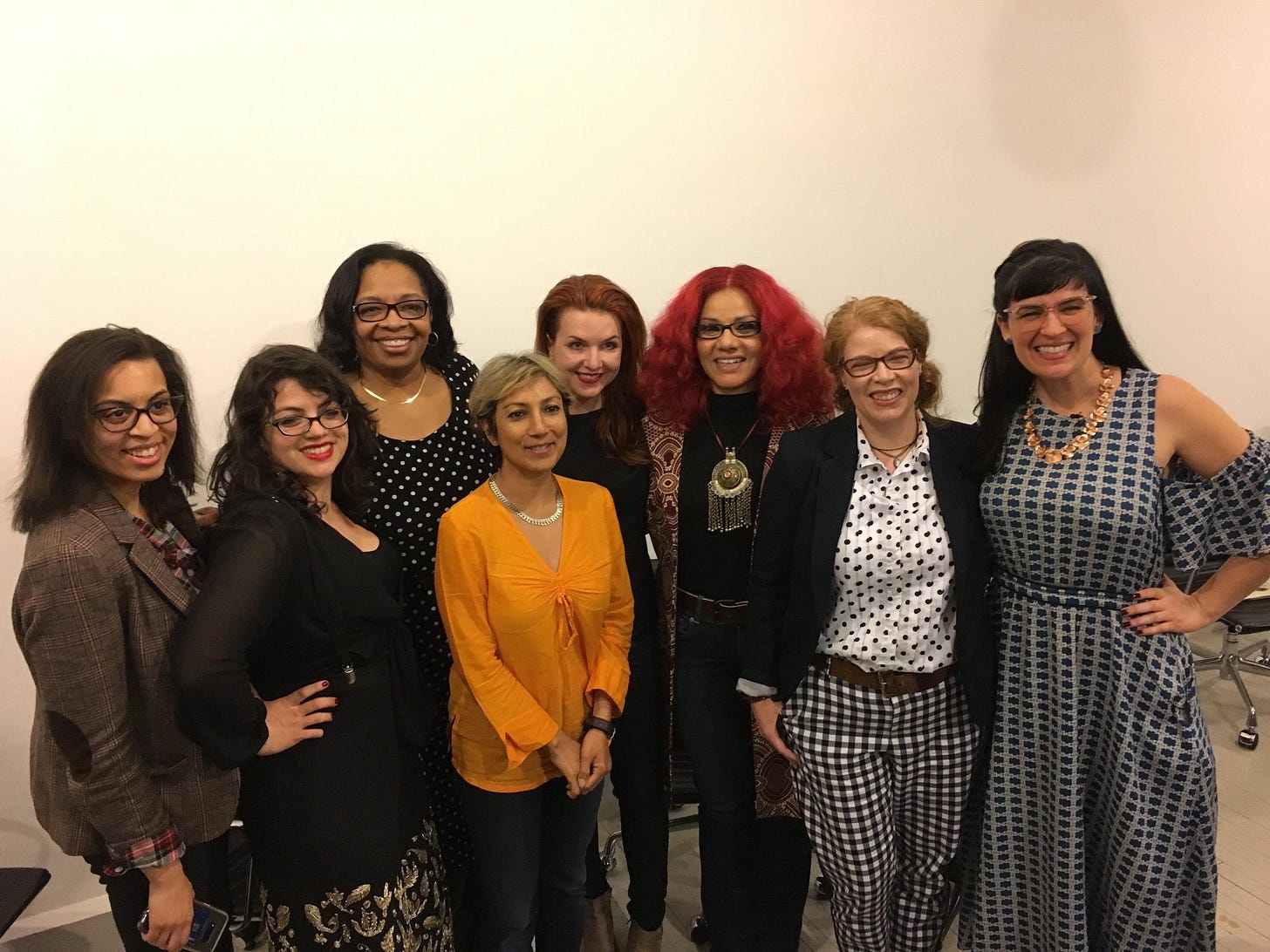 A group of eight women pose in business casual attire. 