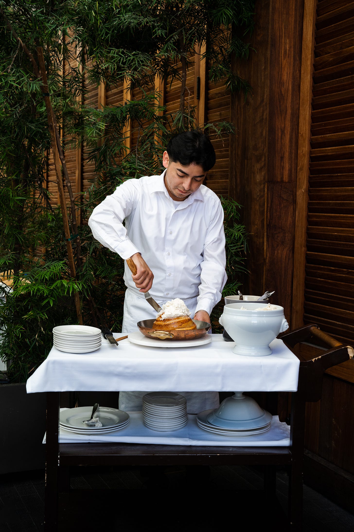 server spreading icing on giant cinnamon roll tableside server spreading icing on giant cinnamon roll tableside