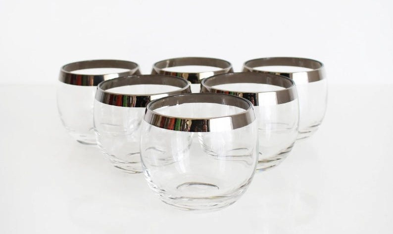 A set of six vintage 1960s silver rim glasses on a white table
