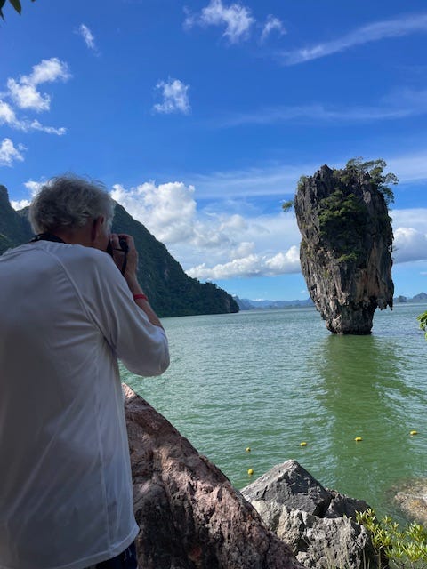 man takes photo of limestone karst island