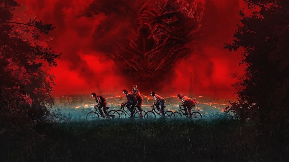 Kids on bicycles ride in front of an ominous red sky that partially hides an evil-looking face