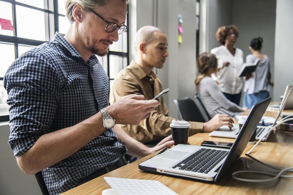 Free Stock Photo of Man working at a laptop and phone in an open office |  Download Free Images and Free Illustrations