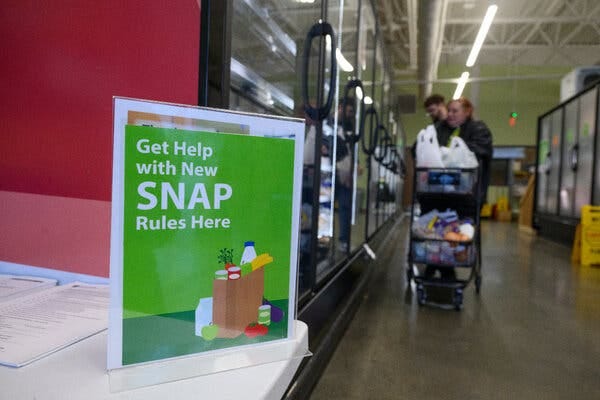 A sign at a food bank says, “Get help with new SNAP rules here.”