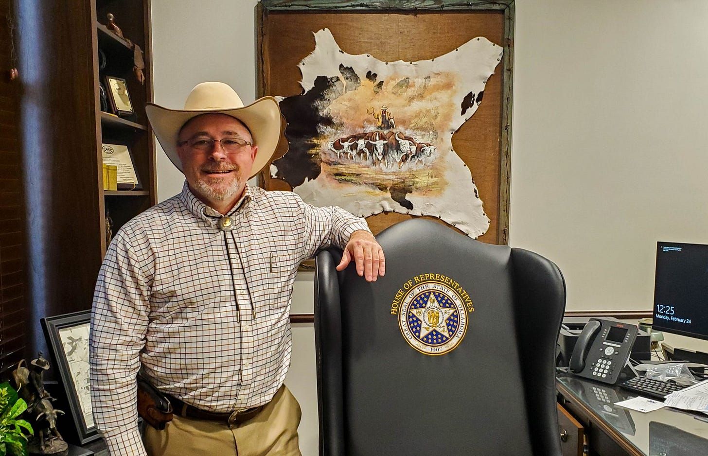 Justin Humphrey stands beside his chair and a calf skin hangs behind him.