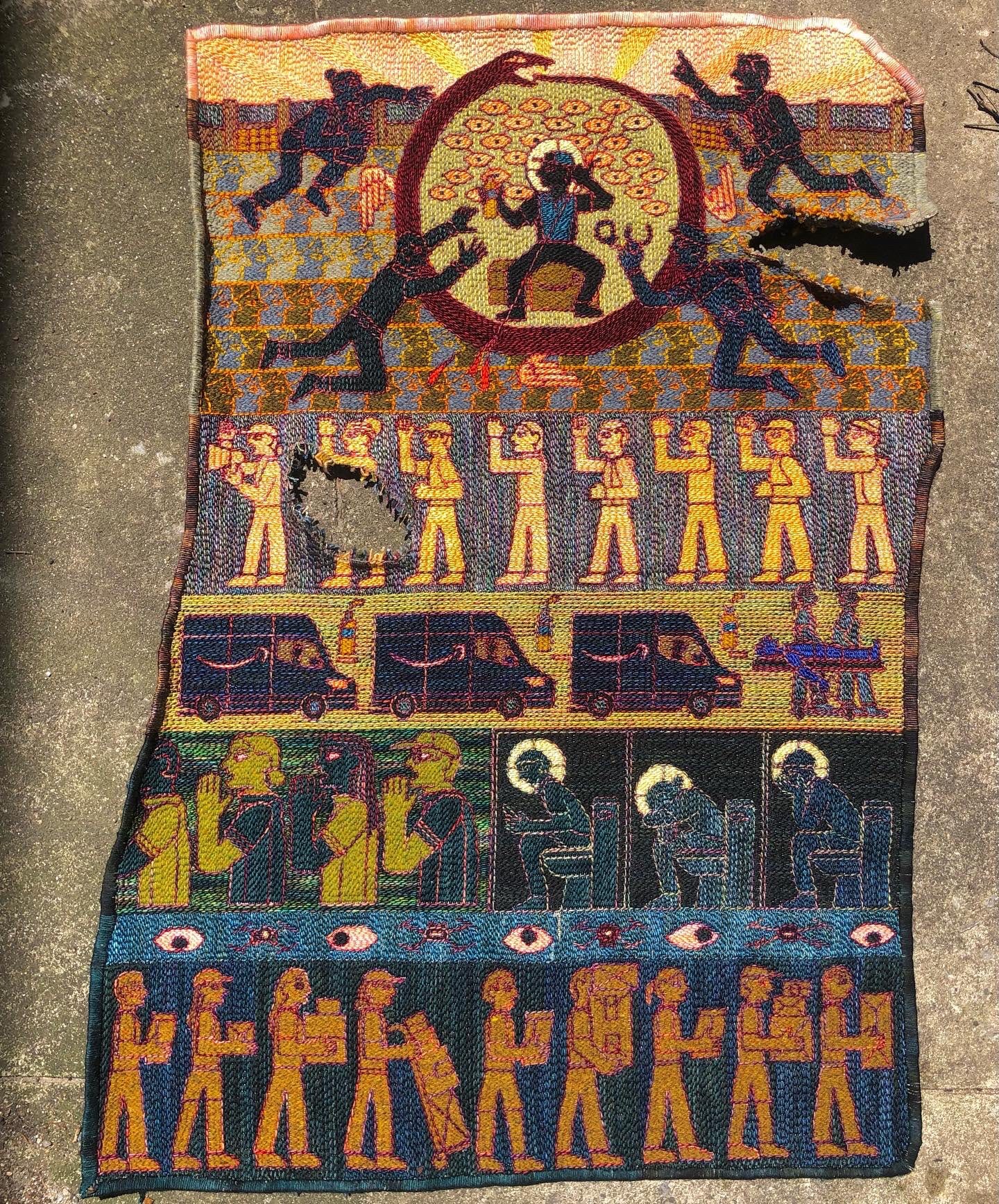 a textile work with tones of blue, purple, yellow, and brown depict an abstract hierarchal scene of human bodies working, amazon cars driving, at the top a worker sits in front of eyes surrounded by an ouroboros snake eating its own tail