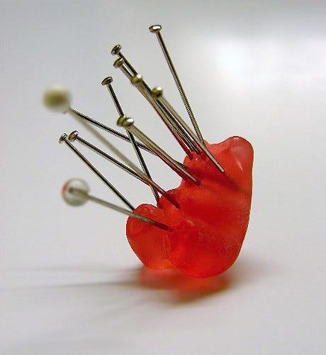 a red gummi bear with a lot of pins stuck in it. "Excessive Death to Gummi Bears" by Furryscaly is licensed under CC BY-SA 2.0. 