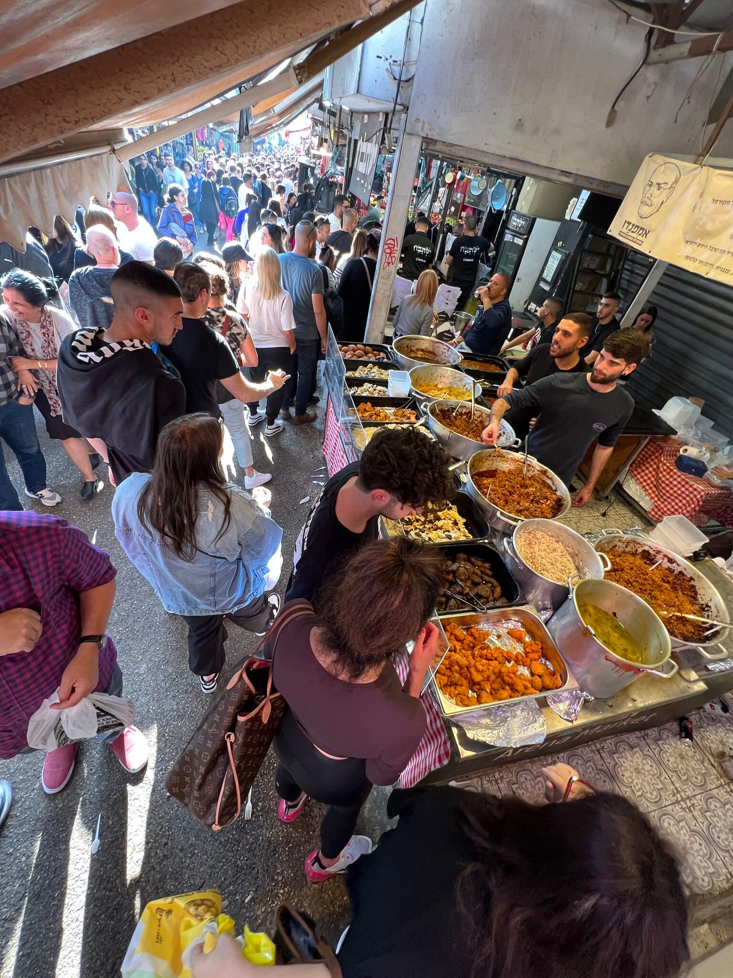 Viele Menschen auf dem Carmel Markt an einem Stand, an dem viele bunte Speisen angeboten werden. Reges Treiben. Viele Menschen auf dem Carmel Markt an einem Stand, an dem viele bunte Speisen angeboten werden. Reges Treiben.