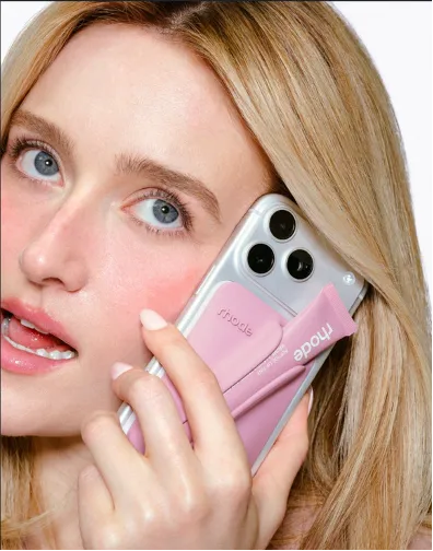Sarah Pidgeon holding a silver iPhone with the pink Rhode Lip Case accessory holding a Sweet Pea Peptide Lip Tint.