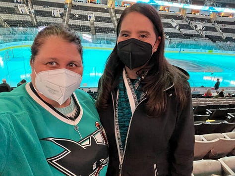 images of hockey arena, 2 girls wearing masks, a mascot shark on ice