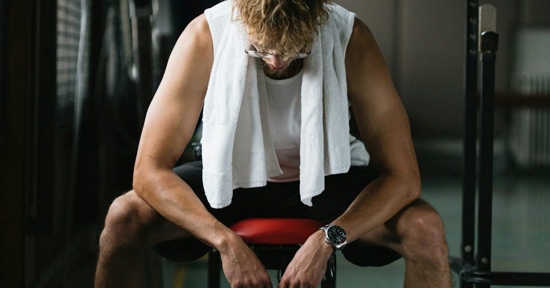 woman in white sleeveless shirt and red shorts sitting on black exercise bench woman in white sleeveless shirt and red shorts sitting on black exercise bench