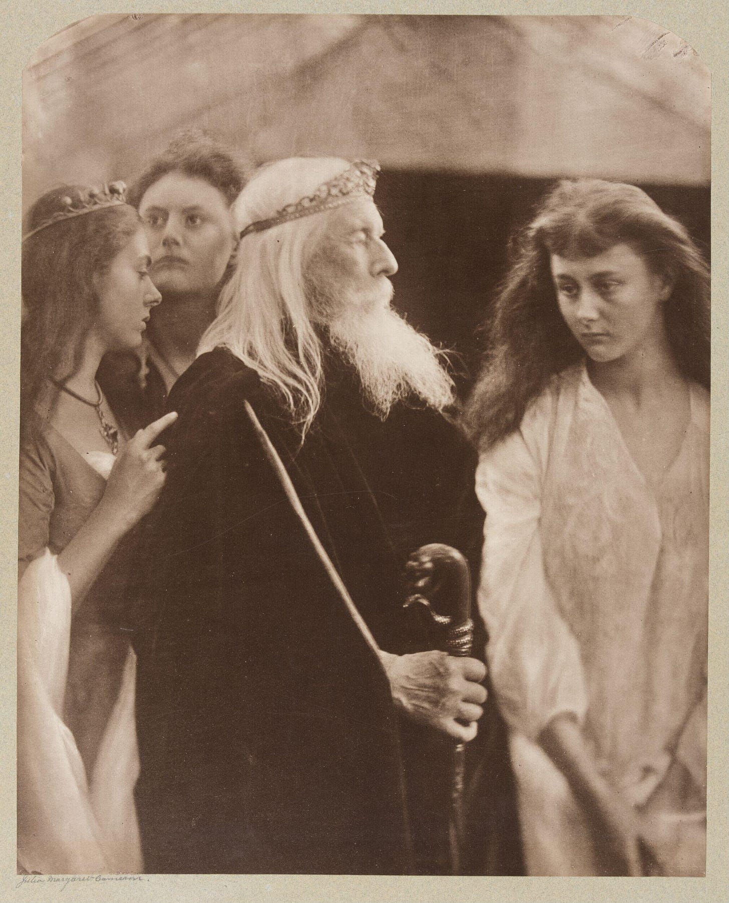 black and white photograph of an old man with a crown in profile, with two young women at his back and one facing him in front black and white photograph of an old man with a crown in profile, with two young women at his back and one facing him in front