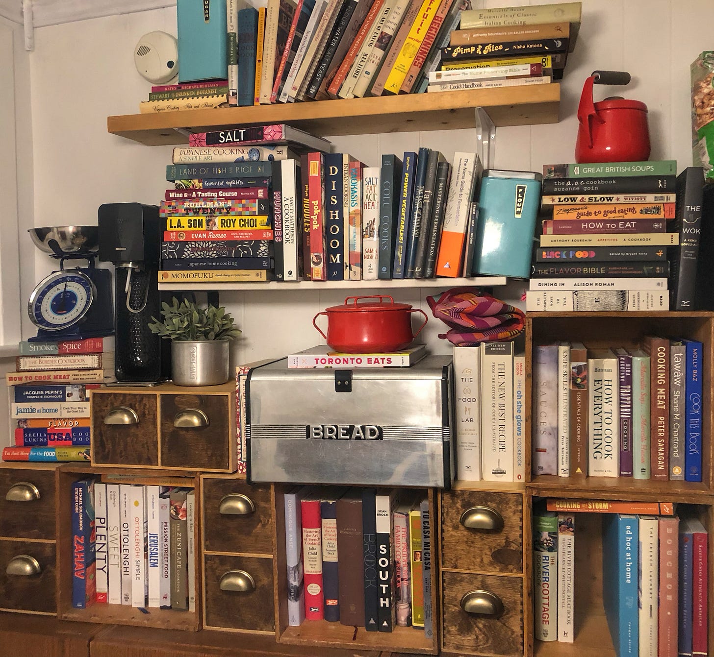 A series of bookshelves full of cookbooks. There is a book missing from the shelf in the lower right corner of the photo.