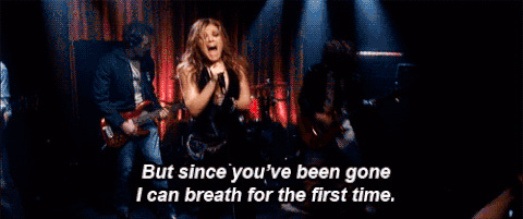 A woman sings into a mic on a dark stage A woman sings into a mic on a dark stage
