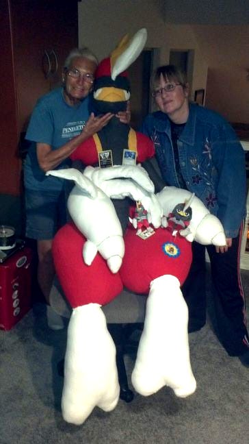 A photograph of Jay’s mother and grandmother, along with a giant Bisharp plush, with smaller plush toys and Pokémon trading cards A photograph of Jay’s mother and grandmother, along with a giant Bisharp plush, with smaller plush toys and Pokémon trading cards