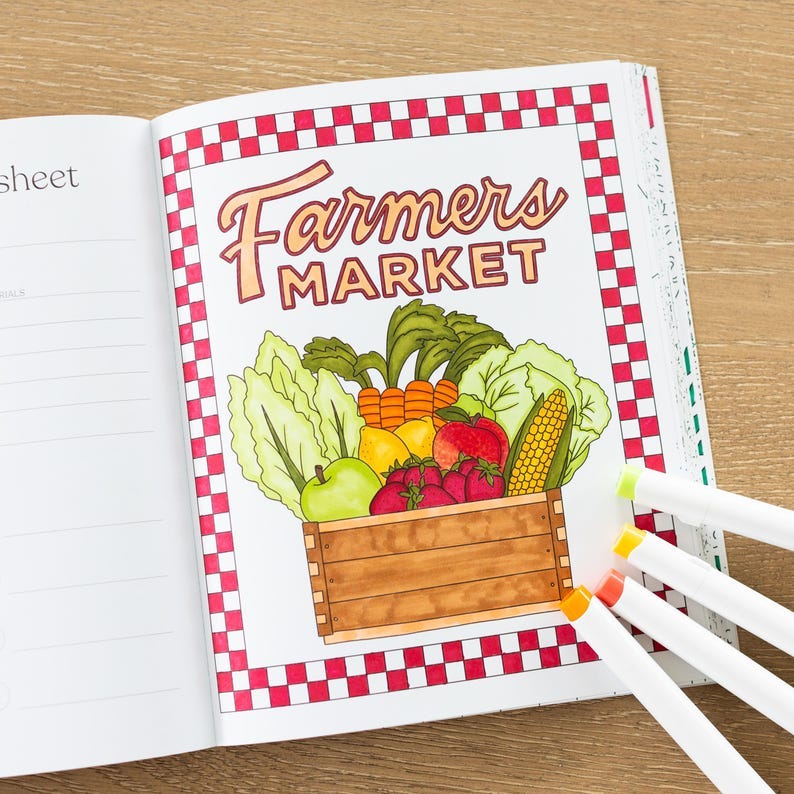 May include: A coloring book page with a red and white checkered border. The page features a drawing of a wooden crate filled with fresh produce, including apples, lemons, carrots, corn, and strawberries. The text "Farmers Market" is written in a stylized font above the crate.