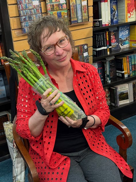 1.A cake decorated with a bridge and cityscape, with “Echoes of the  Lost” written in red across it. 2. Cindy signing books for a crowd lined up next to her. 3. Cindy holding a bunch of asparagus as if it were a bouquet,