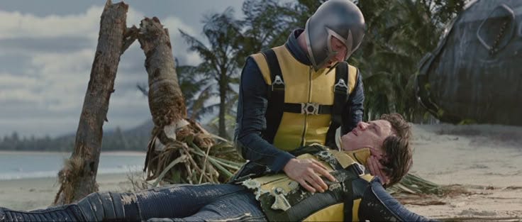 This may contain: two men in yellow and black diving suits are on the beach while one man is laying down