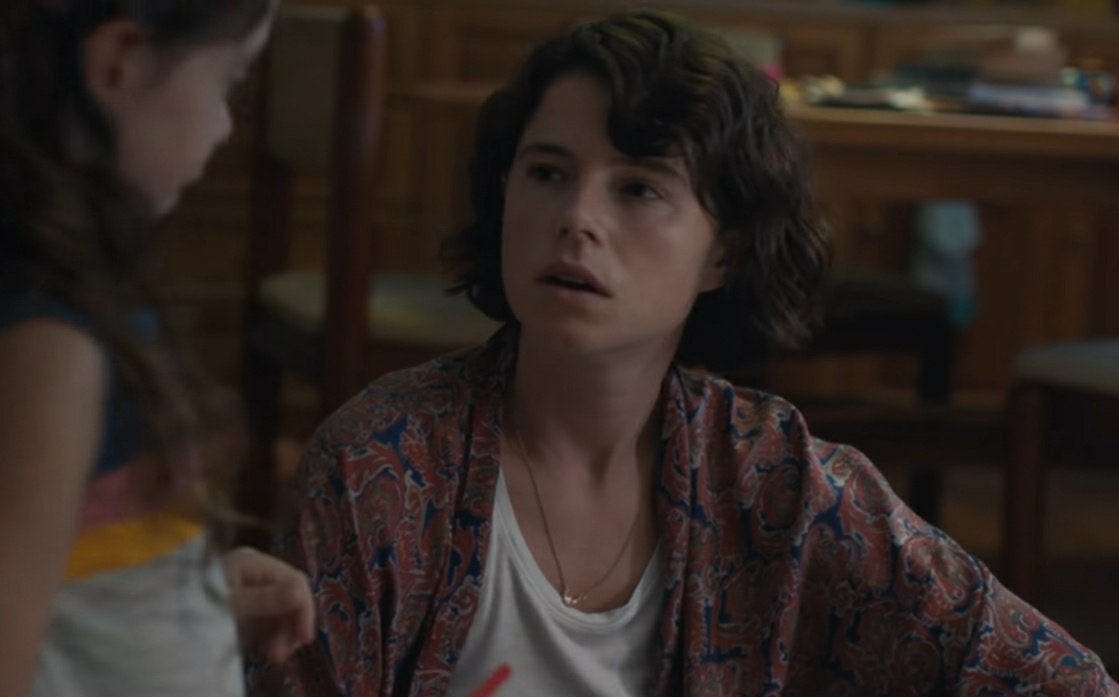 Cena do filme A filha perdida. Mostra uma mulher branca de cabelo chanel olhando para uma criança