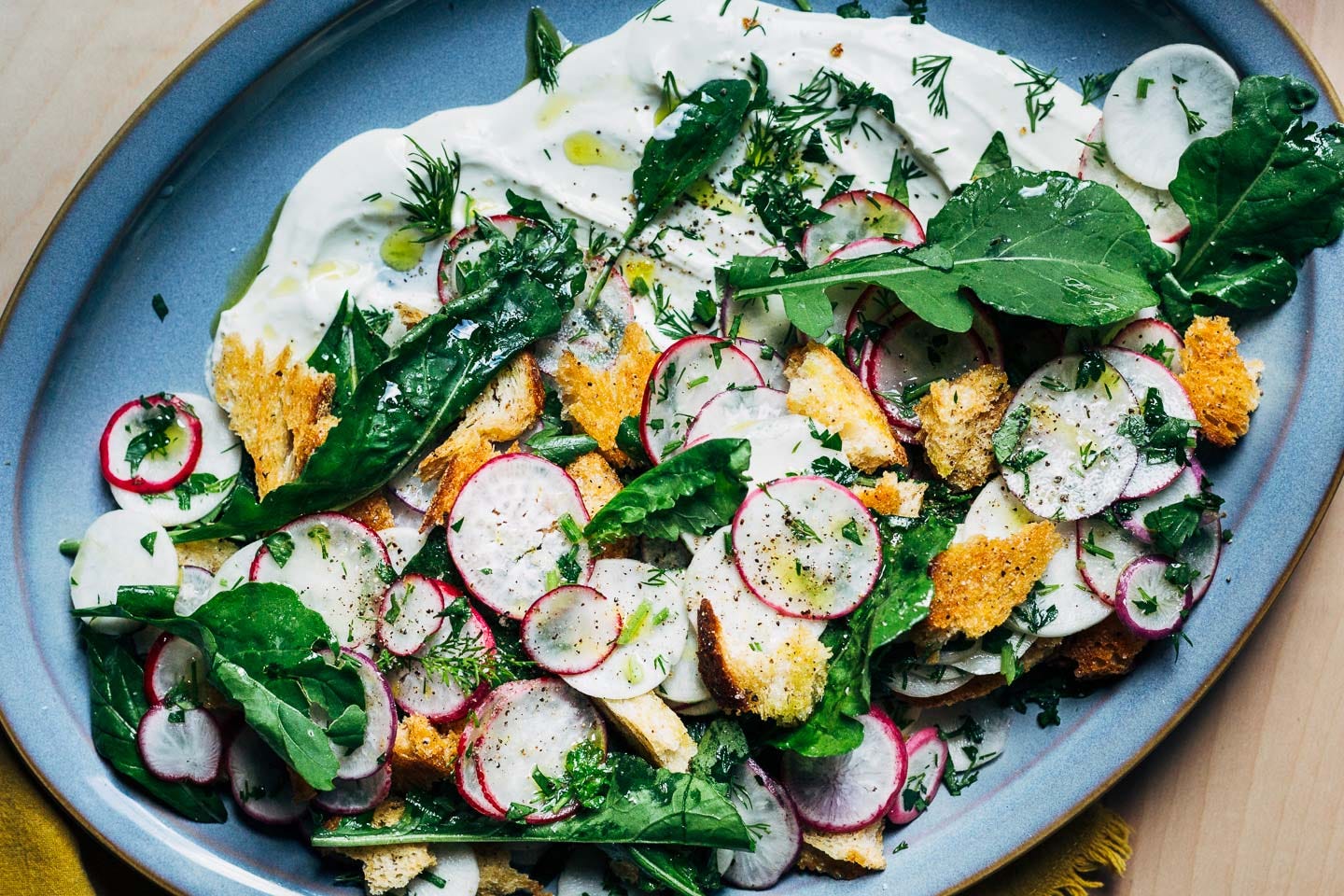 A radish and chevre salad on a blue platter. 