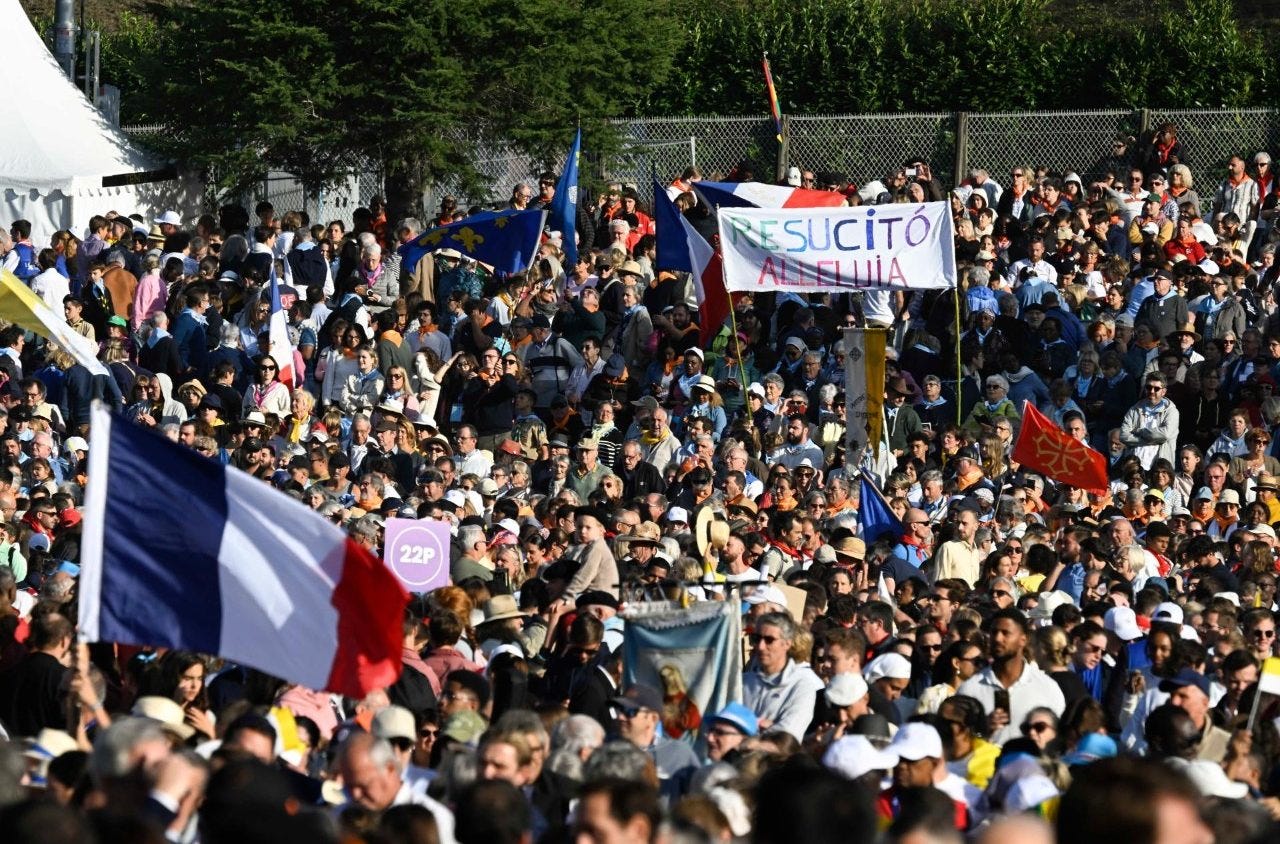 Pilgrims with French flags and a banner at the Lourdes Mass
