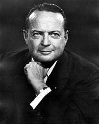 A person in a suit with his hand on his chin

Description automatically generated