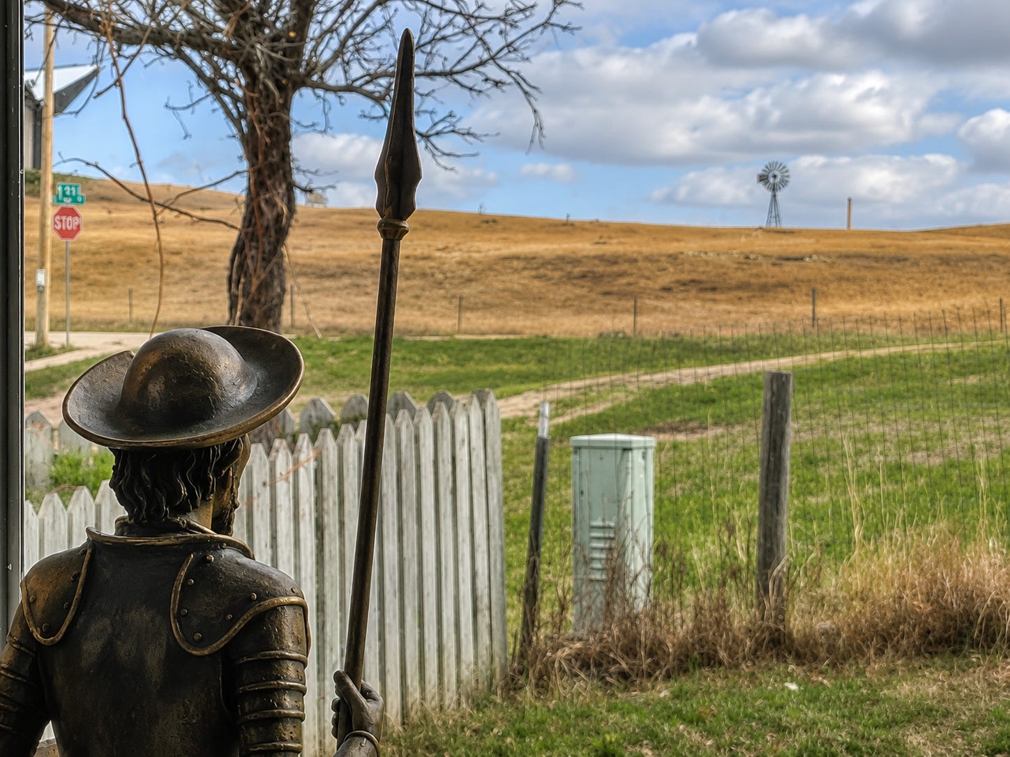 A Don Quixote figurine stands in my window, preparing to tilt at the neighbor's windmill.