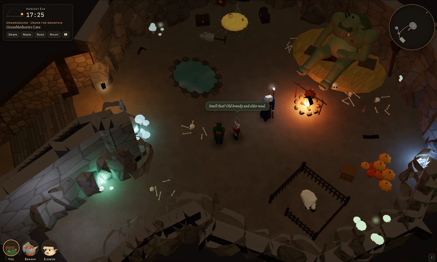 Screenshot of the same low-poly fantasy game, now in a dim underground cave lit by a campfire with a spit roast, glowing pale mushrooms and blue crystals. A huge green troll lies asleep on a straw bed at top right, surrounded by scattered bones and skulls. The cave also holds a small round pool ringed with stones, a yellow rug, chests, a fenced pen with a sheep, a pile of orange pumpkins and a stone stair down the left side. The party stands in the center: the green-clad figure and the red-armored figure facing the blue-robed figure holding a glowing staff by the fire, who says in a speech bubble "Smell that? Old brandy and older mud." The location panel reads "Harvest Eve" "17:25" "Underground · Under the mountain" "Grumblethorn's Cave".