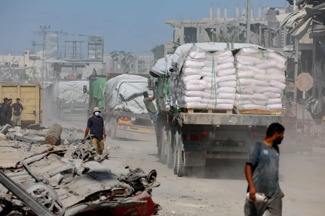 Trucks carry humanitarian supplies through a damaged street in Gaza following the October 2025 ceasefire