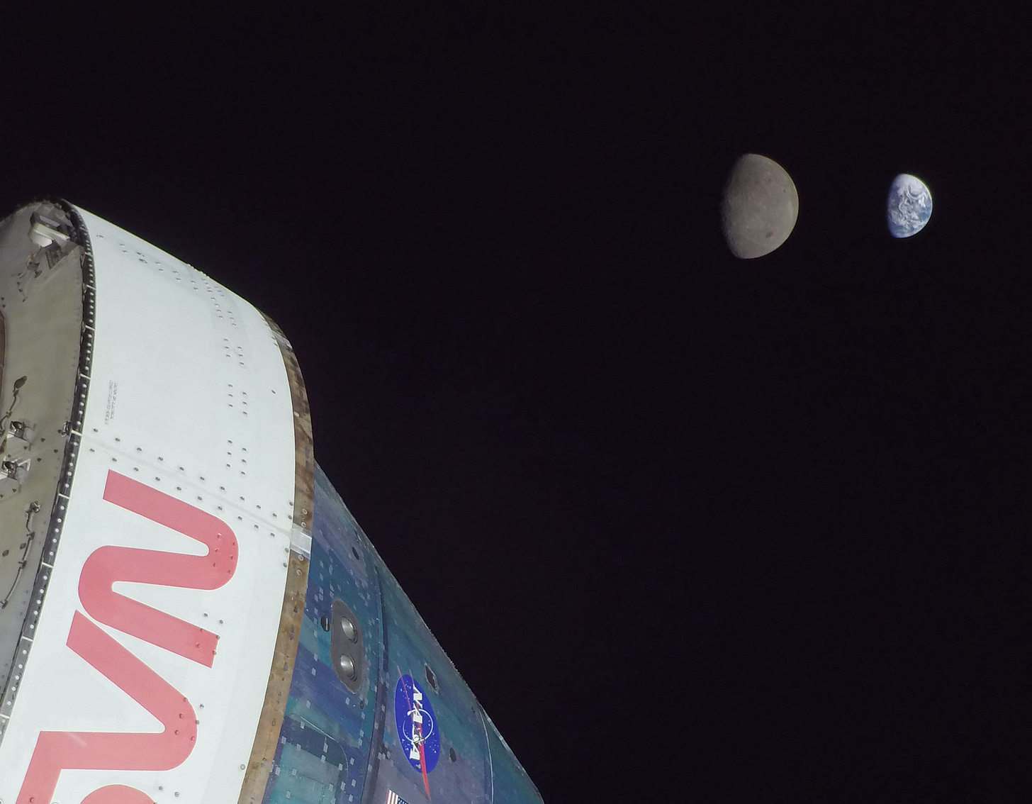 Part of the Orion spacecraft, white adapter and blue-ish Crew Module, with Moon and Earth in distance. Part of the Orion spacecraft, white adapter and blue-ish Crew Module, with Moon and Earth in distance.