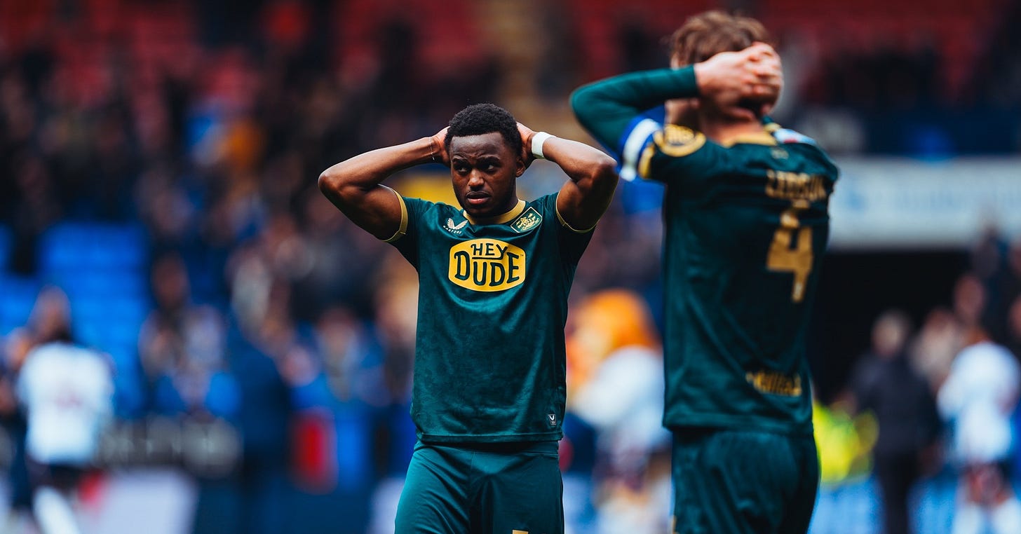 Two Huddersfield Town players, wearing the club’s green third kit, hold their head in their hands. Two Huddersfield Town players, wearing the club’s green third kit, hold their head in their hands.