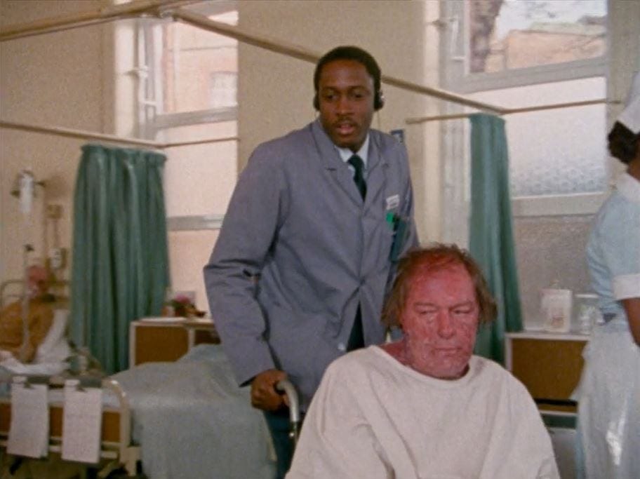 The setting is a hospital ward. A middle-aged white man (Michael Gambon) with a bad skin affliction is pushed in a wheelchair by a young black male porter (Geff Francis) The setting is a hospital ward. A middle-aged white man (Michael Gambon) with a bad skin affliction is pushed in a wheelchair by a young black male porter (Geff Francis)