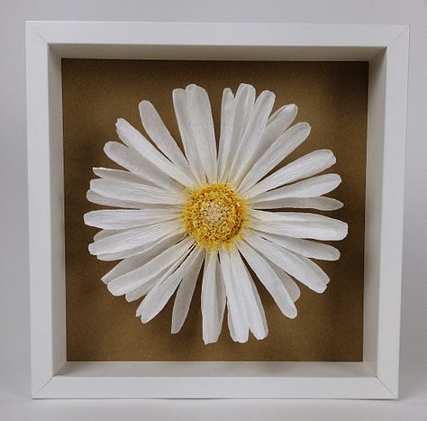 Image one: a paper Daisy, around 7” diameter, the yellow centre coloured with turmeric. Image 2: stems of Poppy and flax set in a small wooden wooden pebble; image 3, a paper sunflower with vivid gold petals and a detailed centre, all coloured with onion skin.