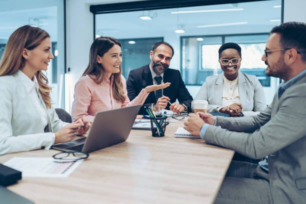 Smiling business persons gathered around a table and talking Smiling business persons gathered around a table and talking