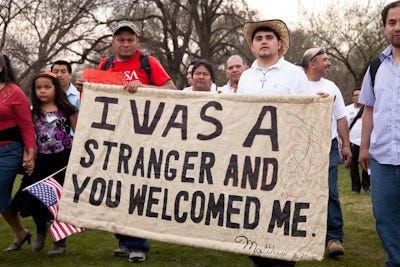 In a demonstration, two men hold a sign with words by Jesus.