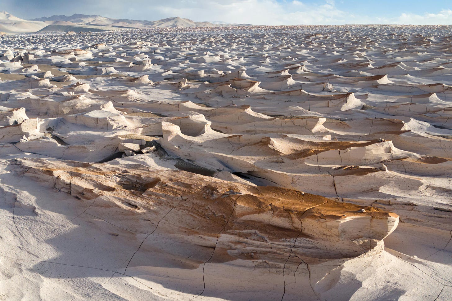 A wide angle shot of sand formations across a desert in the daytime.