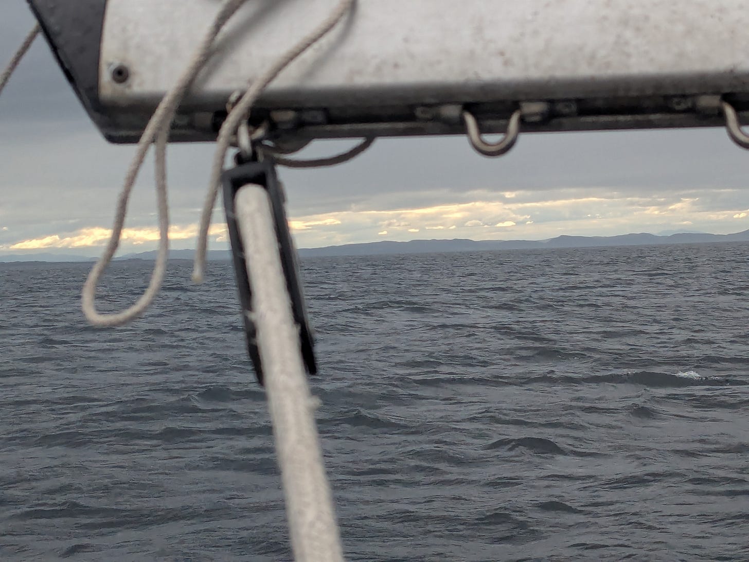 looking out over the water toward the distant hills, with the boom, ropes, and pulley in the foreground