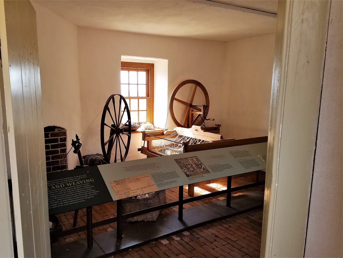 Spinning wheels sit in front of a window in a small building at Monticello.