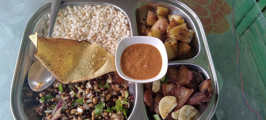 A sekuwa set featuring beaten rice, potatoes, chili sauce, a corn chip, and pork.