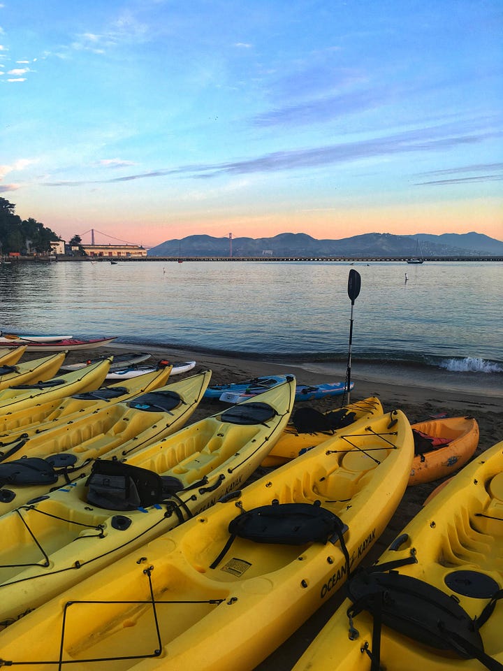 A rescue kayaker on San Francisco Bay during the Escape from Alcatraz triathlon, with the Golden Gate Bridge in the distance.