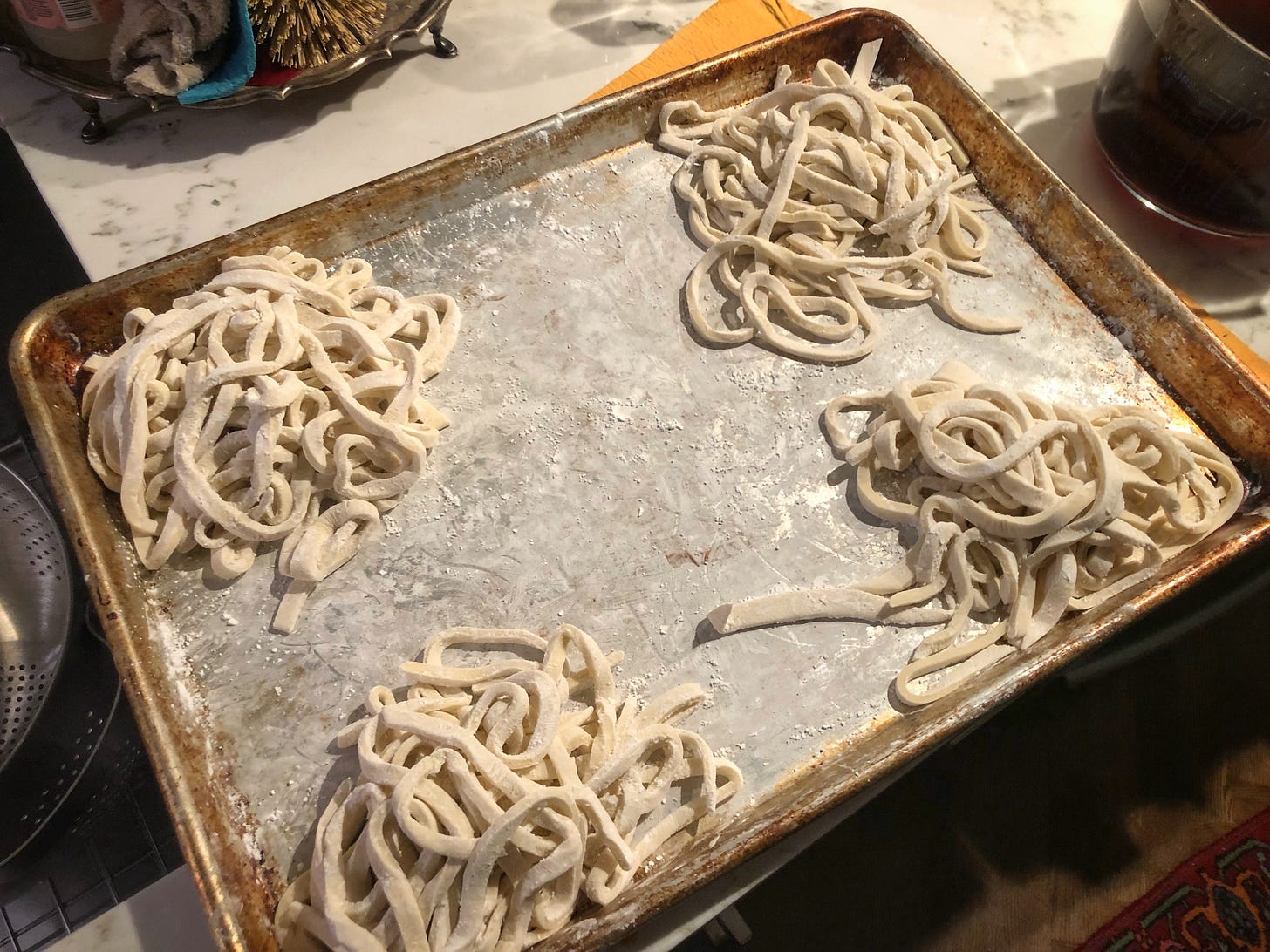 A metal sheet tray with four nests of noodles heavily dusted in corn starch